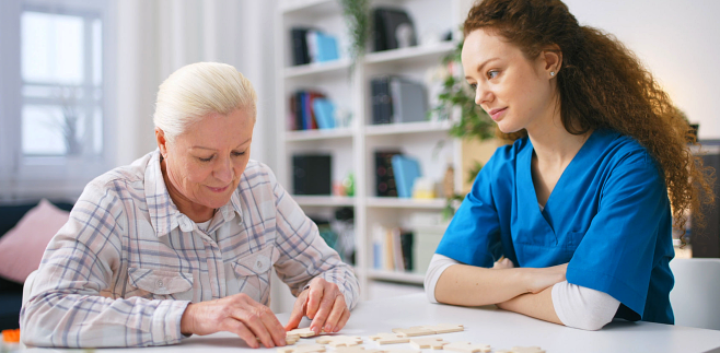 caregiver watching the senior woman solve the puzzle